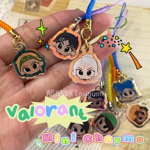 May include: A selection of Valorant mini charms with cartoon character designs. Each charm has a different colour and a gold-coloured clasp with a colourful lanyard. The words "Valorant" are written in green and blue, and "Mini Charms" in pink and yellow.