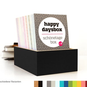 Frontansicht der happydaysbox/schönetagebox in schwarz. In der offenen Kiste sind die Karten des Jahres zu sehen, mit einer Karte für jeden Tag.