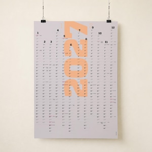 May include: A vertical wall calendar for the year 2022 printed on a light gray background. The year 2022 is displayed in large, bold, peach-colored numerals centered on the page. Twelve columns of black numbers represent the days of each month.