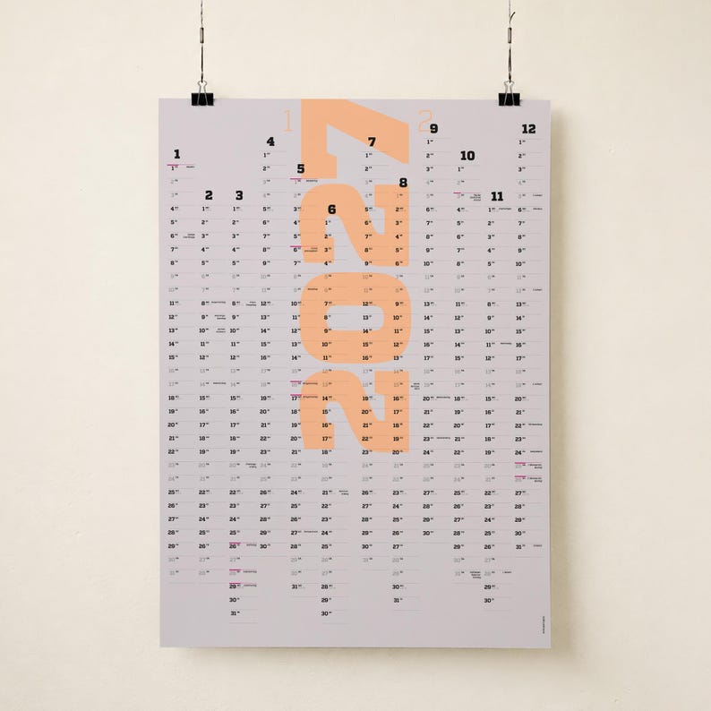 May include: A vertical wall calendar for the year 2022 printed on a light gray background. The year 2022 is displayed in large, bold, peach-colored numerals centered on the page. Twelve columns of black numbers represent the days of each month.