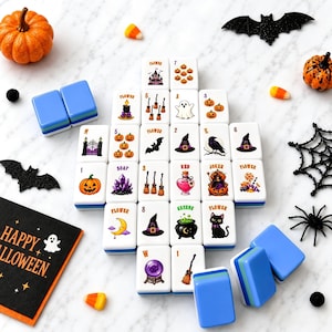 May include: A set of white mahjong tiles featuring colorful Halloween-themed illustrations including pumpkins, ghosts, bats, witches' hats, black cats, and cauldrons. The tiles are arranged in a grid alongside decorative plastic bats, spiders, and candy corn.