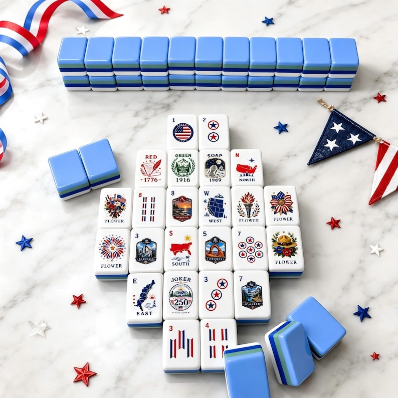 May include: A set of white mahjong tiles featuring colorful illustrations of American landmarks, nature, and patriotic symbols. The tiles are arranged in a grid with some stacked in rows. The set includes blue-backed tiles and small star-shaped accents.