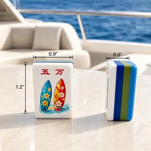 Puede incluir: Dos fichas de Mahjong blancas con dise&ntilde;o de tabla de surf. Una ficha presenta una tabla azul y amarilla, la otra una tabla roja y blanca. Las fichas miden 3 cm de alto, 2,3 cm de ancho y 1,5 cm de grosor.