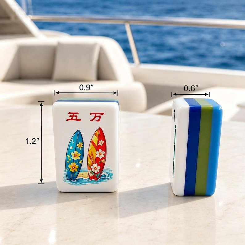 Puede incluir: Dos fichas de Mahjong blancas con dise&ntilde;o de tabla de surf. Una ficha presenta una tabla azul y amarilla, la otra una tabla roja y blanca. Las fichas miden 3 cm de alto, 2,3 cm de ancho y 1,5 cm de grosor.