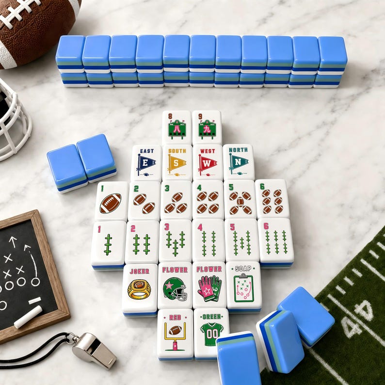 May include: A set of white mahjong tiles featuring football-themed graphics, including numbered footballs, directional flags, and sports equipment. The tiles have blue, green, and white layered backs. Additional tiles are stacked in rows.