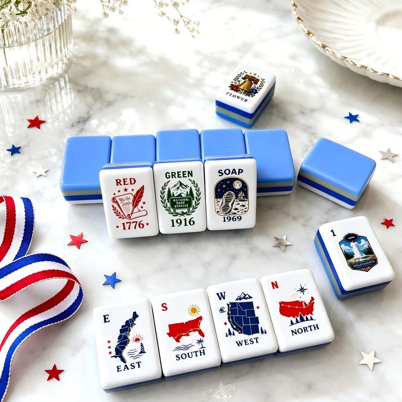 May include: A set of rectangular mahjong tiles with light blue backs and white faces featuring various colorful illustrations and text including RED 1776, GREEN 1916, SOAP 1969, EAST, SOUTH, WEST, NORTH, and a Liberty Bell design labeled FLOWER.