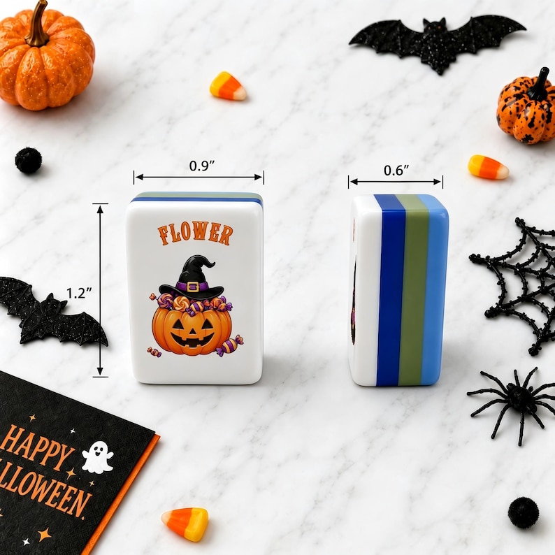 May include: Two rectangular mahjong tiles featuring a Halloween design with a jack-o'-lantern wearing a witch hat and the word FLOWER. The tiles measure 0.9 inches wide, 1.2 inches high, and 0.6 inches deep, with blue and green striped side panels.