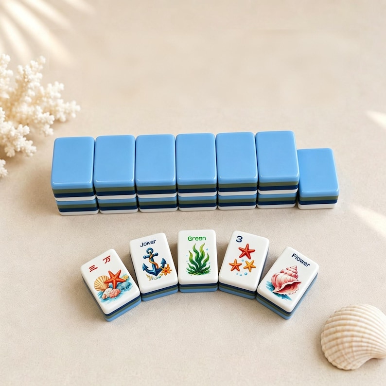 May include: A collection of blue and white Mahjong tiles with marine-themed designs. The tiles display images of starfish, seashells, and anchors. The set includes tiles with the words "Joker", "Green", and "Flower".