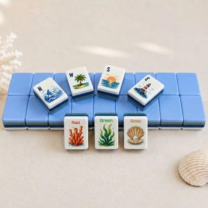 May include: A set of decorative Mahjong tiles with a coastal theme. The tiles feature images of a lighthouse, palm tree, sunset, and coral. The tiles are arranged on a blue base, with additional tiles displaying the words "Red", "Green", and "Soap".