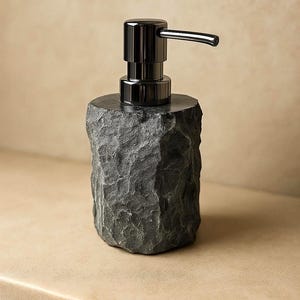 Może przedstawiać: Ciemnoszary dozownik mydła z teksturowaną, kamienną podstawą i elegancką, czarną metalową pompką. Dozownik ma nowoczesny design i nadaje się do łazienki lub kuchni. Pompka ma długi dzióbek.