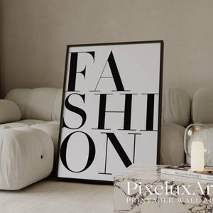 Puede incluir: Un cuadro en blanco y negro con la palabra "FASHION" en negrita. El cuadro se exhibe en un salón moderno, junto a un sofá blanco, una mesa de centro con tapa de mármol y una pequeña lámpara.