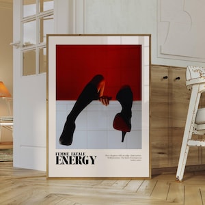 May include: Framed art print featuring a striking image of legs and high heels against a red backdrop. The print includes the words "FEMME FATALE ENERGY" in bold text, with additional text below. The artwork is displayed in a room with wooden floors.