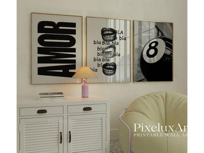 May include: Three framed wall art prints. The first says "AMOR" in large black letters. The second features lips and the word "bla". The third shows a black and white eight ball. The prints are in gold frames.