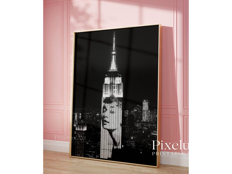 May include: Black and white framed print featuring the Empire State Building with a woman's face superimposed over the building. The print has a gold frame and is displayed against a pink wall. The text "Pixelu Printable" is visible in the bottom right corner.