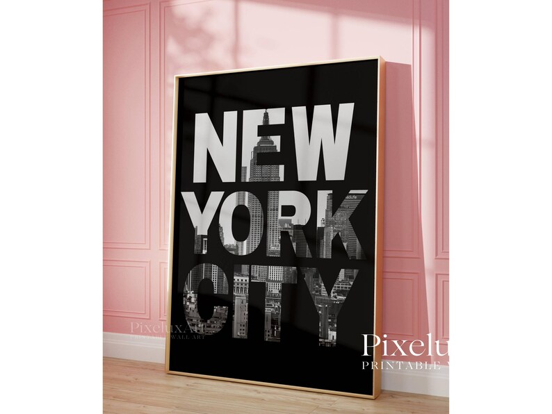 May include: A framed black and white print featuring the words "NEW YORK CITY" in large, bold letters. The letters are filled with a grayscale image of the city's skyline. The print is displayed in a room with pink walls.