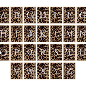 Könnte beinhalten: Eine Sammlung von 26 rechteckigen Kunstdrucken, die jeweils einen Buchstaben des Alphabets zeigen. Die Buchstaben sind mit einem funkelnden, diamantartigen Design verziert. Der Hintergrund jedes Drucks hat ein braunes und schwarzes Leopardenmuster.