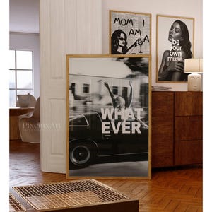 May include: A selection of framed art prints in a contemporary style. One print shows a person in a car with the text "WHATEVER". Other prints feature a woman with the text "MOM I AM A" and a portrait with the text "be your own muse."
