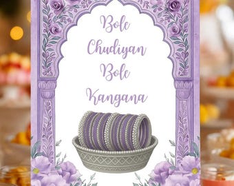 May include: A watercolor-style sign with the text "Bole Chudiyan Bole Kangana" in elegant script. The sign features a floral arch design with purple flowers and a basket of bangles. The sign is displayed on a small wooden easel.