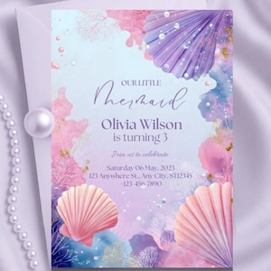 Può includere: Un biglietto d'invito a tema sirena con un design ad acquerello. La carta presenta una conchiglia viola e rosa, coralli e il testo "Our Little Mermaid". Include il nome "Olivia Wilson" e i dettagli della celebrazione.