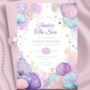 Könnte beinhalten: Einladung zur Geburtstagsparty mit Meerjungfrauen-Motiv mit dem Text "Under The Sea". Das Design zeigt Aquarellillustrationen von Muscheln, Korallen und Wasserpflanzen in Lila-, Rosa- und Türkistönen. Die Einladung enthält Datum, Uhrzeit und RSVP-Informationen.