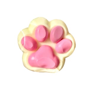 May include: A paw-shaped item with a pale yellow outer layer and pink pads. The pads are smooth and glossy, contrasting with the matte finish of the surrounding material. The design is a playful representation of a pet's paw.