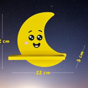 May include: A yellow crescent moon-shaped shelf with a smiling face, measuring 22 cm wide and high, and 5 cm deep. The shelf is set against a starry night sky background. A decorative item for a child's room.