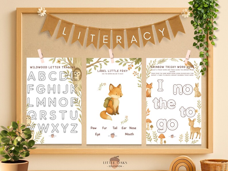 Op de afbeelding: Een educatieve display met houten frame met drie werkbladen voor kinderen. De bladen bevatten het traceren van letters, het labelen van een vos en een woordjacht. De banner hierboven luidt "LITERACY". Het thema is bosdieren en leren.