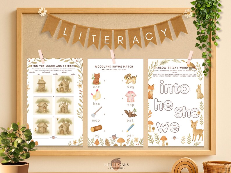 Op de afbeelding: Een houten educatieve display met drie bedrukte werkbladen. De werkbladen bevatten illustraties met bosmotieven en tekst voor lees- en schrijfactiviteiten. Een banner met de tekst "LITERACY" hangt erboven.