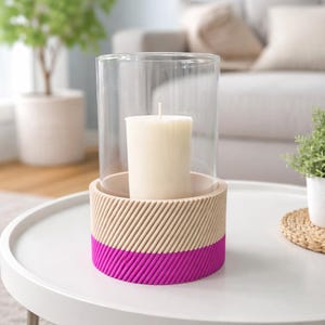 Può includere: Un portacandele decorativo con un cilindro di vetro trasparente. La base è beige con linee diagonali e una vivace fascia magenta. Una candela bianca è all'interno, creando un'atmosfera calda. Ideale per l'arredamento della casa.