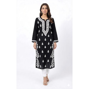 May include: A black long-sleeve tunic with intricate white floral embroidery. The tunic features a round neckline and is paired with white pants. The embroidery is concentrated around the neckline, cuffs, and along the front of the tunic.