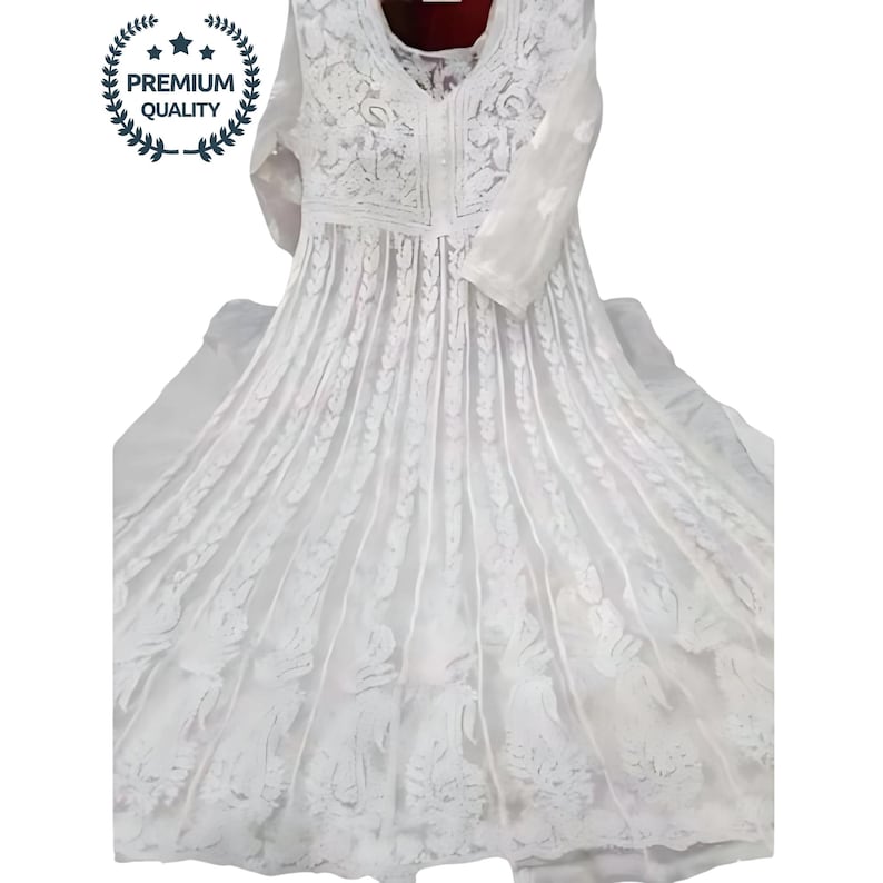 May include: A white, long-sleeved dress with intricate floral embroidery. The dress features a V-neckline and a flowing skirt. The image includes a "PREMIUM QUALITY" seal. The dress is made of a lightweight fabric.