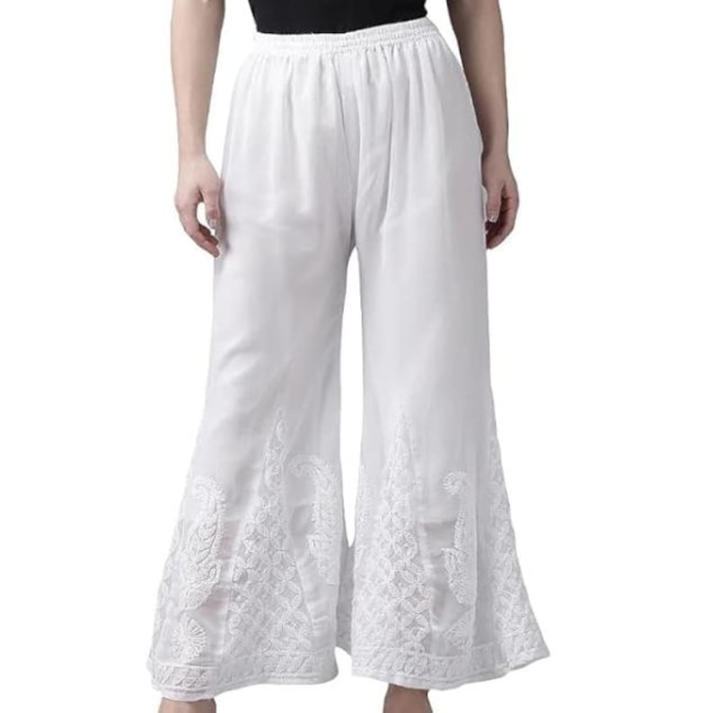 May include: White palazzo pants with intricate embroidered floral patterns near the hem. The wide-leg pants have a comfortable, flowing design. The pants are made of a lightweight fabric, perfect for warm weather.
