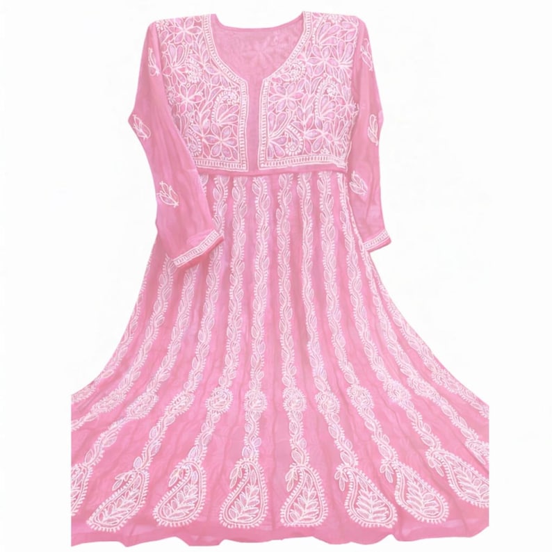 May include: A pink, long-sleeved dress with intricate white embroidery. The dress features a V-neckline and a flowing skirt. The embroidery includes floral and paisley patterns, creating a delicate and detailed design. The dress is made of a lightweight fabric.