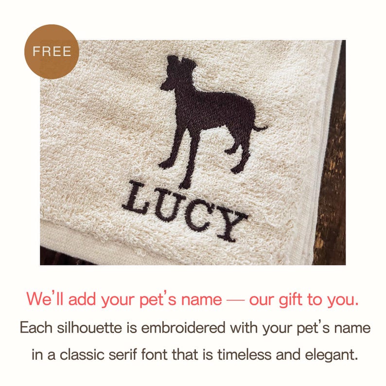 Puede incluir: Una toalla beige con una silueta de perro marr&oacute;n oscuro y el nombre "LUCY" bordado en una fuente serif cl&aacute;sica. Una etiqueta "FREE" est&aacute; en la esquina superior izquierda. La toalla est&aacute; doblada y parece estar hecha de un material suave y absorbente.