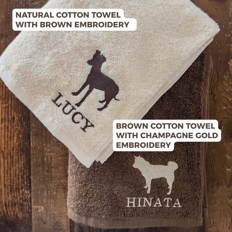 Puede incluir: Dos toallas de algod&oacute;n con bordado de perro. La toalla superior es natural con bordado marr&oacute;n y el nombre "LUCY". La toalla inferior es marr&oacute;n con bordado dorado champ&aacute;n y el nombre "HINATA". Las toallas tienen el texto "NATURAL COTTON TOWEL WITH BROWN EMBROIDERY" y "BROWN COTTON TOWEL WITH CHAMPAGNE GOLD EMBROIDERY".