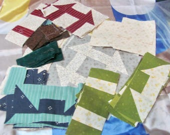 Può includere: Vari pezzi di tessuto in vari colori e motivi, tra cui disegni di frecce rosse e bianche, strisce verdi e bianche e forme geometriche blu. Questi pezzi sono probabilmente per progetti di quilting o patchwork.