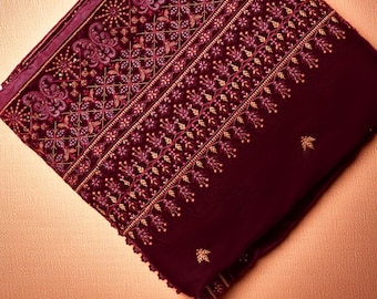 May include: A folded, burgundy textile with intricate embroidery. The design features floral and geometric patterns in shades of gold and purple. The fabric appears to be velvet or a similar plush material, with a detailed border.