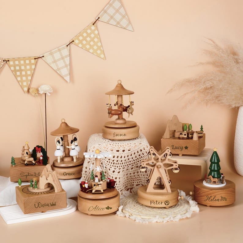 May include: A collection of wooden music boxes featuring various designs including carousels, a Ferris wheel, a train, and a Christmas tree. Each box is engraved with names such as Sophia, Grace, Emma, Lucy, Olivia, Alice, Peter, and Helen.