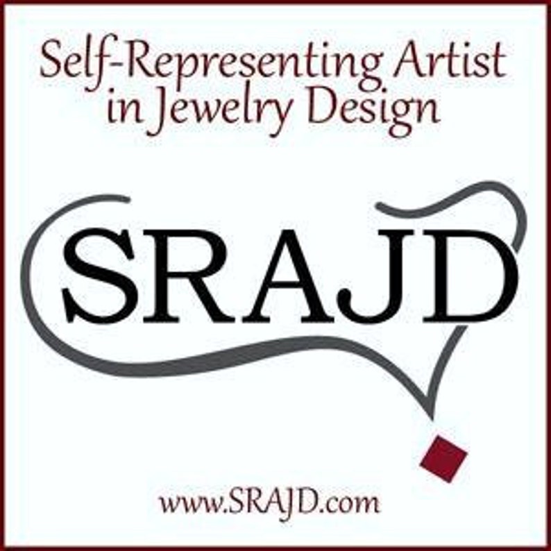 May include: Logo for a jewellery design company called "SRAJD", which stands for "Self-Representing Artist in Jewellery Design". The logo is a stylised wordmark in black with a grey curved line around it. The website address "www.SRAJD.com" is displayed below the logo.