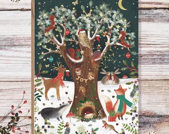 May include: A Christmas card featuring a whimsical illustration of a tree with twinkling lights, decorated with ornaments and surrounded by woodland creatures. The tree is adorned with the word "JOY" and features a variety of animals, including a deer, a fox, a badger, and a hedgehog.