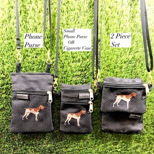 May include: Three black canvas bags with a zipper closure and a mesh front panel. The bags have a black strap and a gold clasp. The bags are embroidered with a brown and white dog. The bags are labeled "Phone Purse", "Small Phone Purse OR Cigarette Case", and "2 Piece Set".