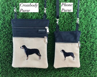 Puede incluir: Dos bolsos de bandolera negros y beige con cierre de cremallera y correas ajustables. El bolso más grande tiene el texto "Dixie Bags" en la parte delantera. Ambos bolsos presentan una imagen bordada de un perro blanco y negro.