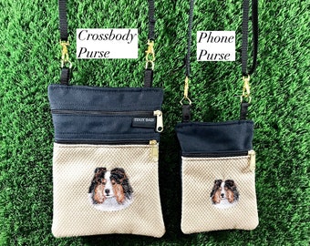 Op de afbeelding: Twee zwarte canvas tassen met een bruine mesh bodem. De grotere tas is gelabeld "Crossbody Purse" en de kleinere tas is gelabeld "Phone Purse". Beide tassen hebben een ritsvak en een geborduurd beeld van een hond.