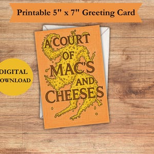 May include: A greeting card with the text "A Court of Mac's and Cheeses" in brown lettering, with a yellow illustration. The card is 5" x 7" and is a digital download. The card is on a wooden surface.
