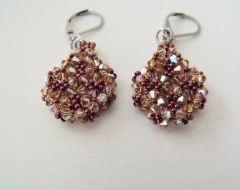 May include: A pair of dangle earrings with a teardrop-shaped design. The earrings are made of brown and clear beads.