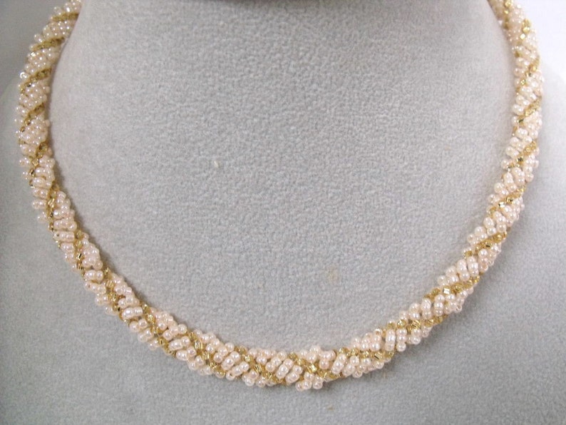 May include: A gold and white beaded necklace with a twisted design.