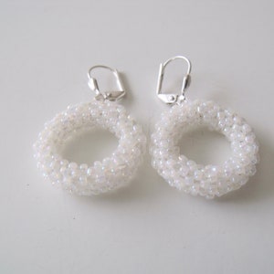 May include: A pair of white beaded hoop earrings with silver hooks.