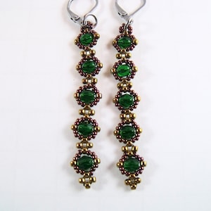 May include: A pair of long, dangling earrings with green and brown beads. The earrings are made with small, round beads that are strung together in a pattern. The earrings are attached to silver hooks.