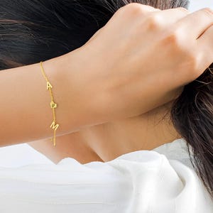 Pulsera personalizada con nombre en oro, letras mayúsculas y corazón. Regalo único para mujeres, mamás y amigas. Joyería fina y elegante.