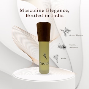 May include: A frosted glass perfume bottle with a dark wood cap, labelled "Kashish." The image includes text that reads "Masculine Elegance, Bottled in India." Illustrations of orange blossom, Spanish labdanum, and musk are also present.